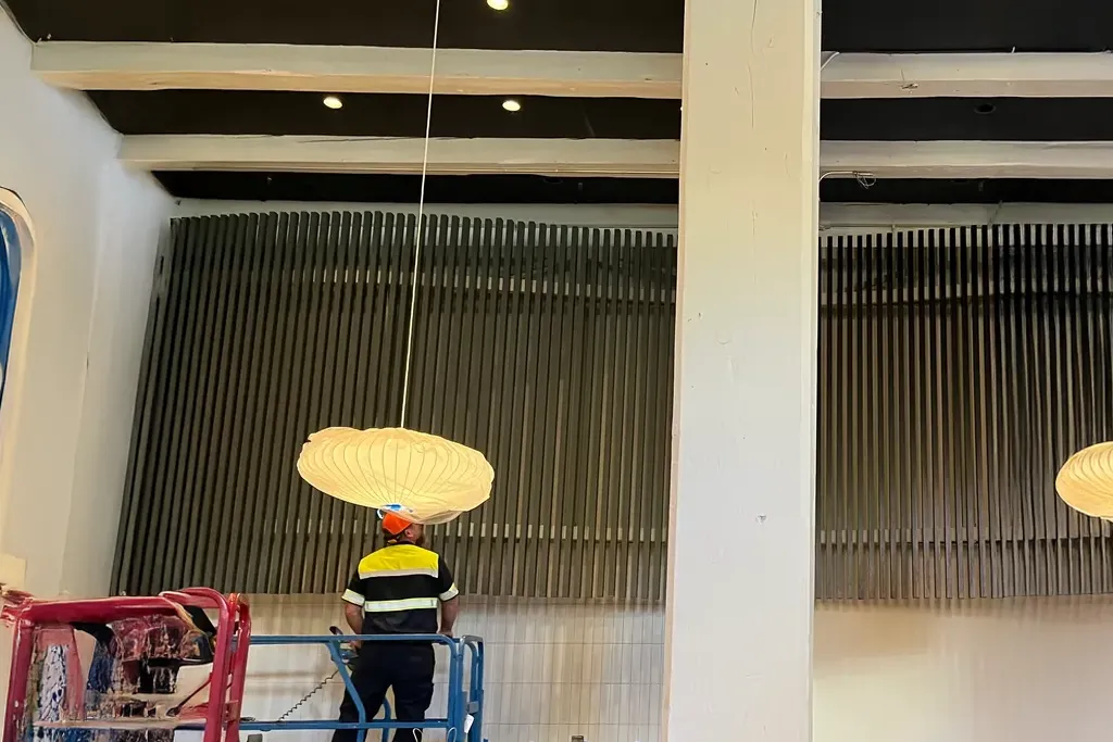 Specialized rigging team from Jacked Co. using a scissor lift to install a large-scale architectural art piece.