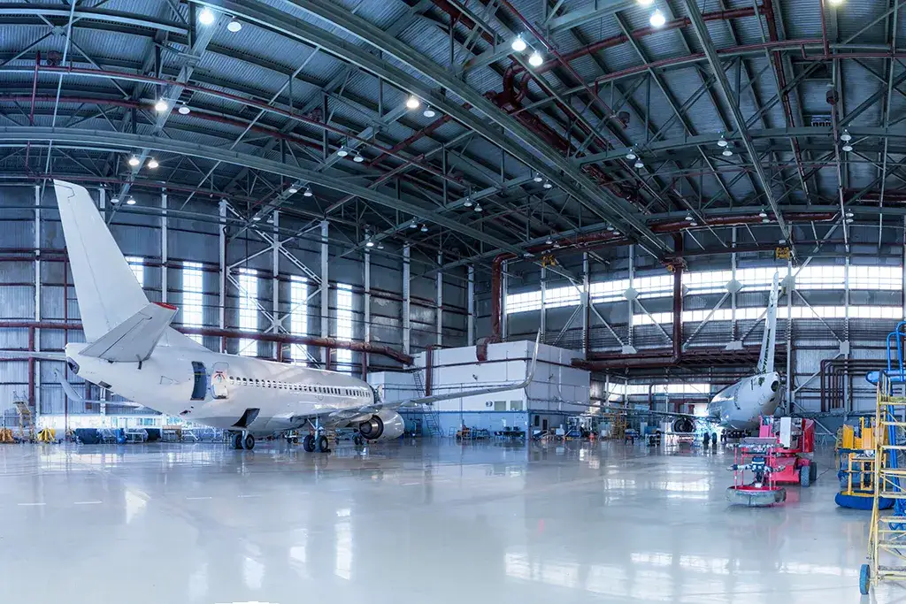 Industrial rigging services for the aviation industry inside a large aircraft hangar with commercial planes.
