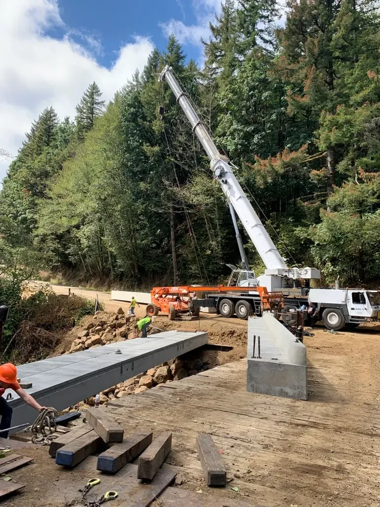 Jacked Co. mobile crane and crew installing concrete bridge girders for a rural infrastructure project.
