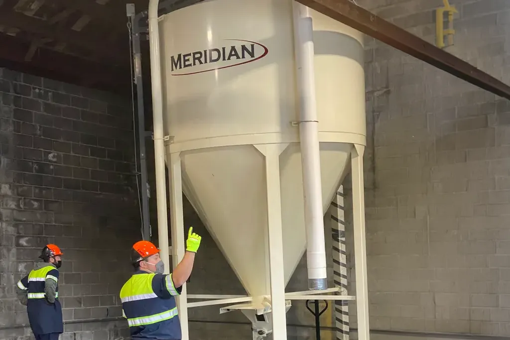 Jacked Co. rigging crew positioning a large Meridian stainless steel storage silo inside a food processing plant.