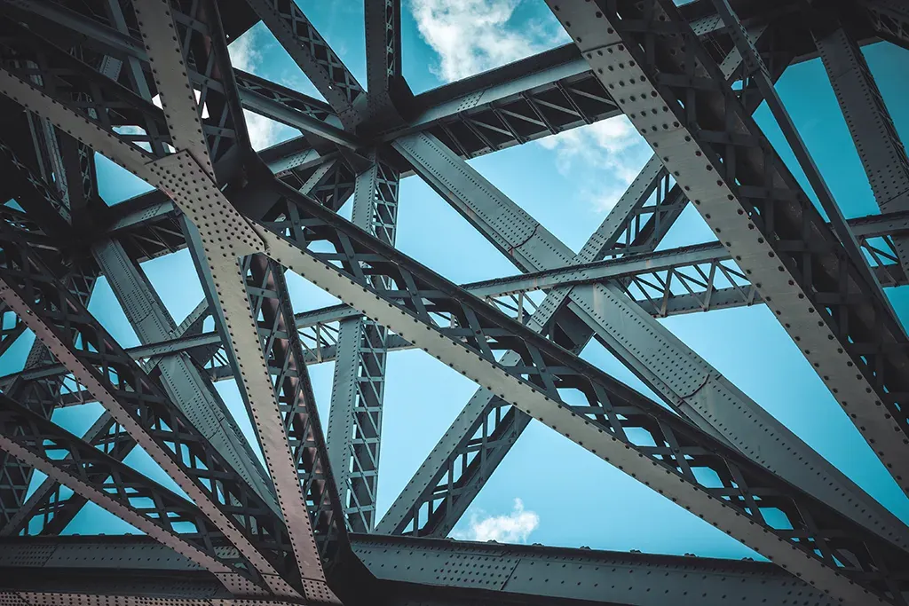 Abstract architectural view looking up through the interlocking steel girders of a civil engineering bridge project.