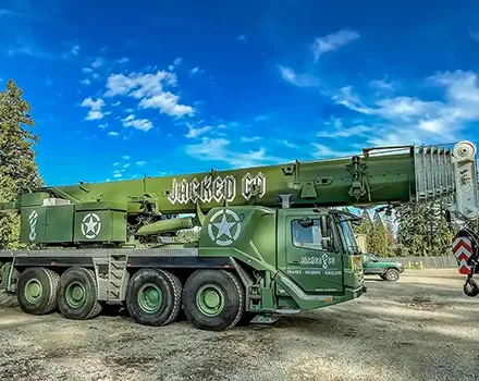 Side profile of the custom olive drab Jacked Co. mobile crane featuring "Cranes Rigging Hauling" branding.