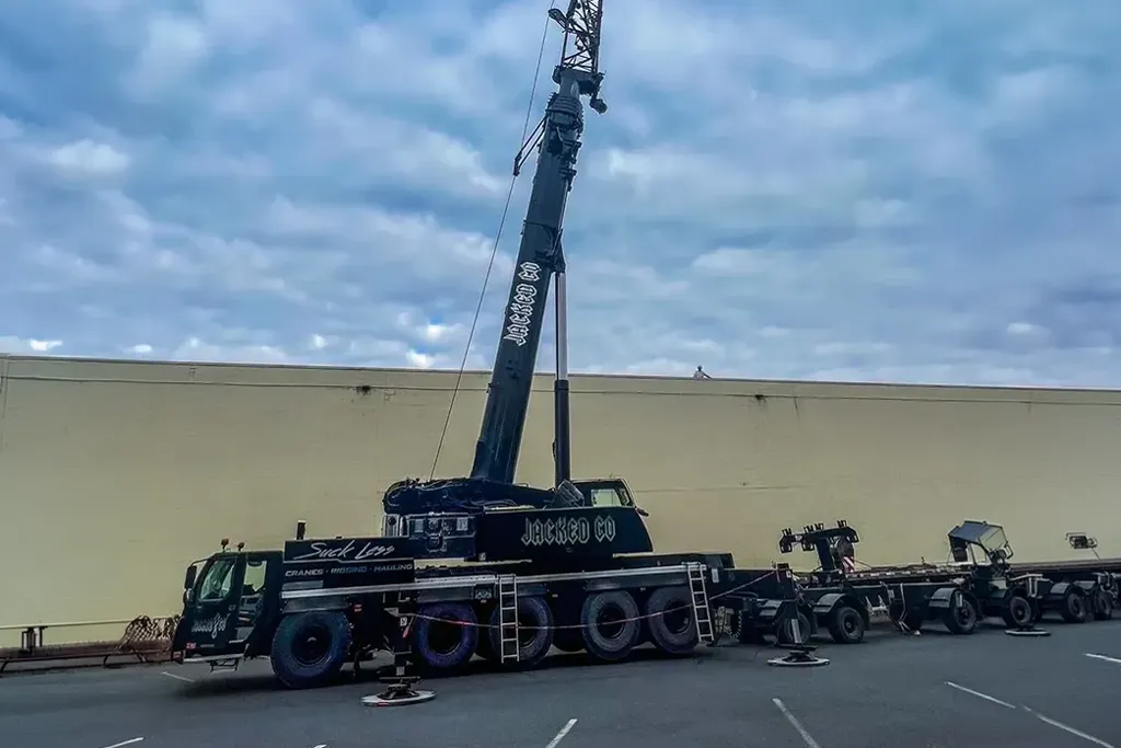 Profile view of a black Jacked Co. branded crane prepared for a heavy rooftop hoist at a commercial warehouse.