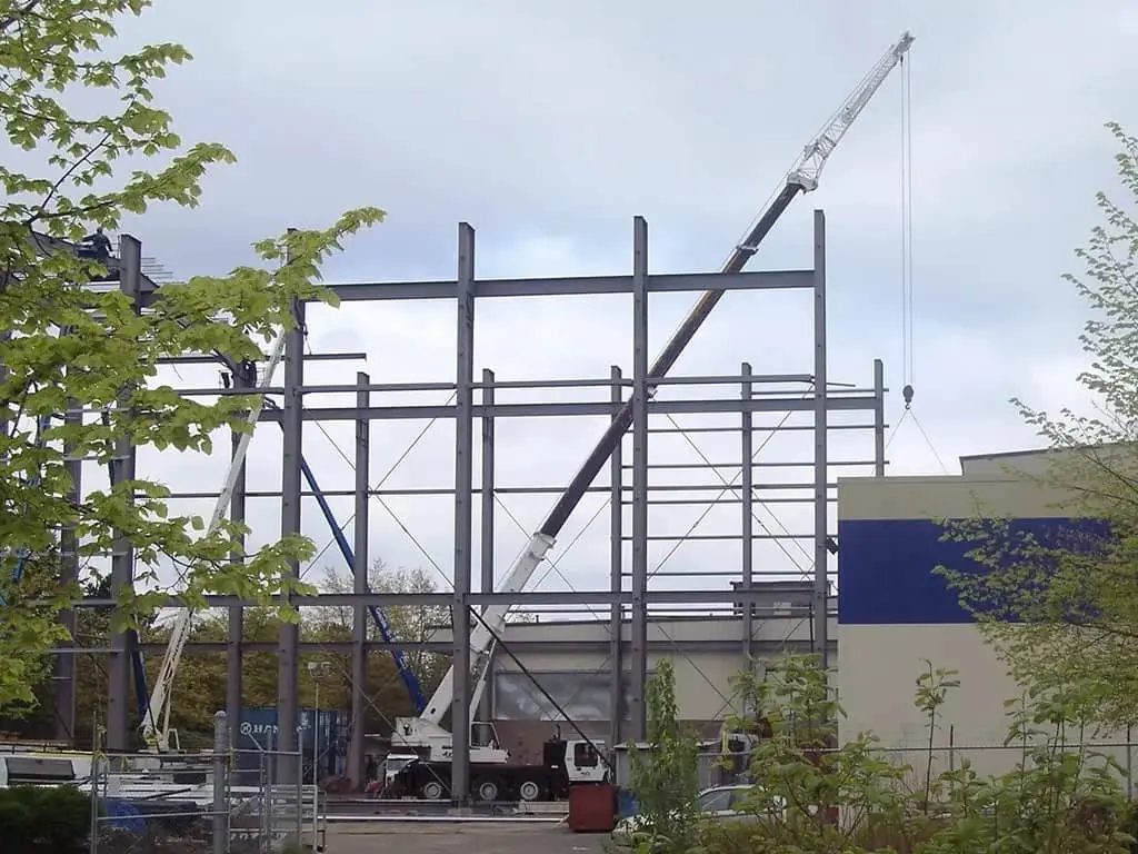 Large mobile crane erecting the steel frame skeleton for a multi-story commercial infrastructure project.