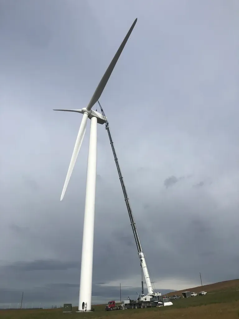 Jacked Co. high-reach crane performing maintenance on a massive wind turbine for the renewable energy sector.