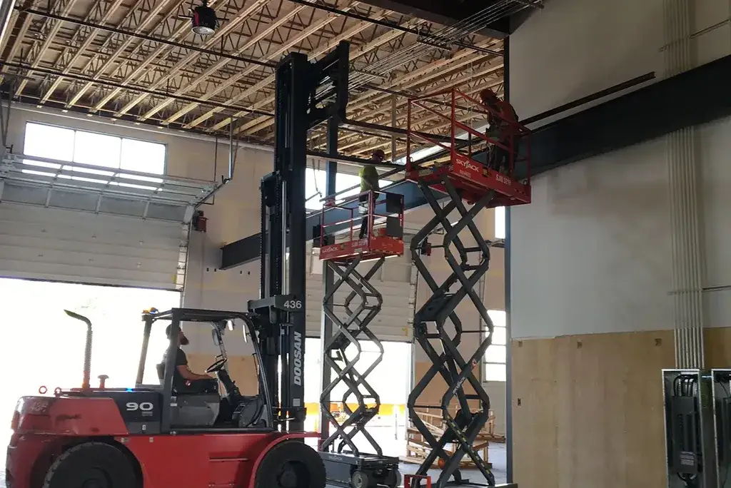 Jacked Co. crew using a Doosan forklift and scissor lifts for structural steel installation inside a processing plant.
