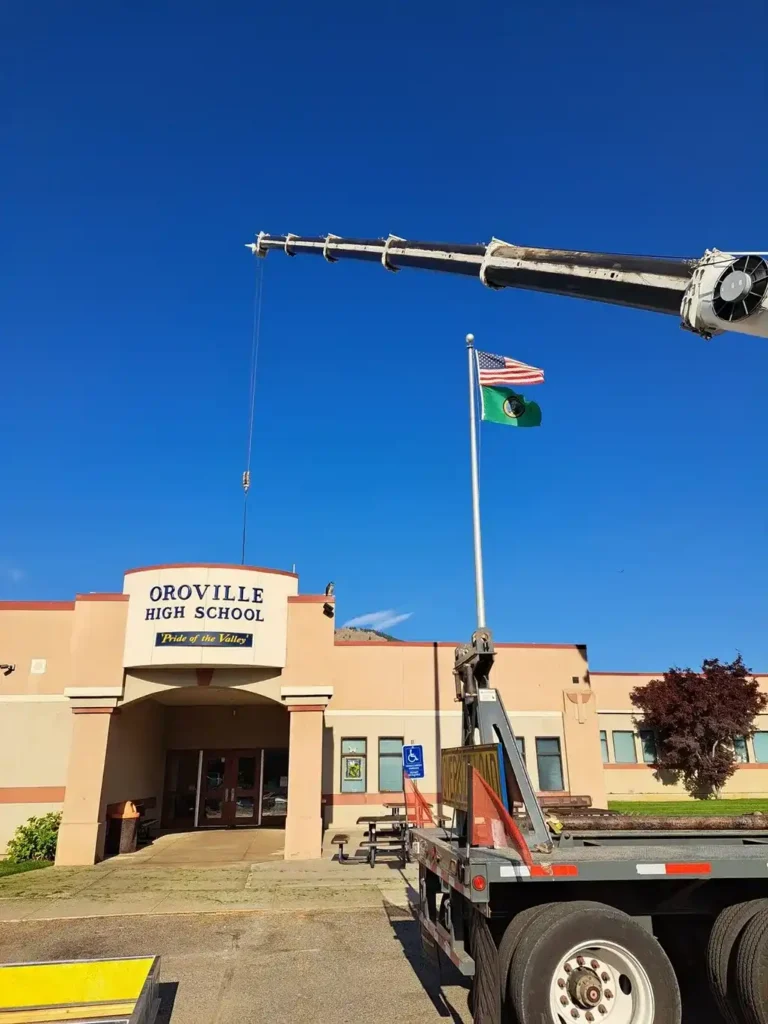 Jacked Co. mobile crane performing facility maintenance at Oroville High School under a clear blue sky.