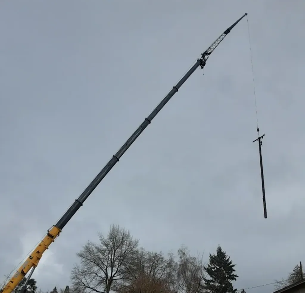 Jacked Co. crane boom fully extended to install a new utility pole during a public infrastructure project.